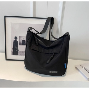 Close-up of black nylon tote bag showing the Shu Nuo brand tag and woven zipper details