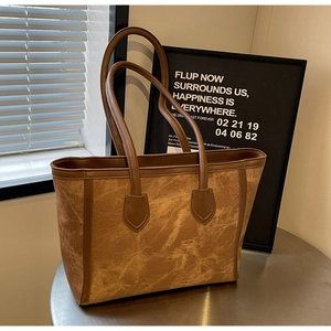 Detail of vintage brown tote bag showing worn texture and leather strap in soft lighting