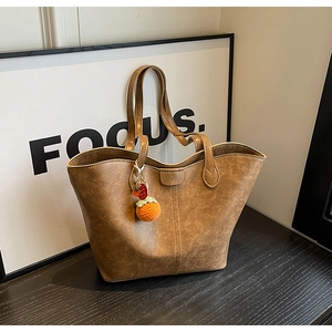 Detailed close-up of brown vintage leather tote bag with orange persimmon charm