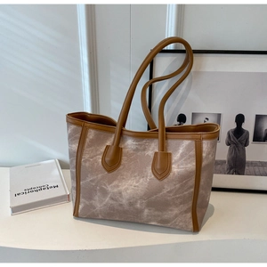 Detail of large tote bag showing marble pattern fabric and brown faux leather straps