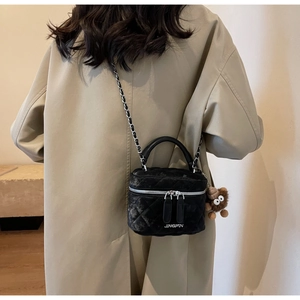 Detail of black velvet quilted chain bag with JINGPIN logo and brown plush animal charm