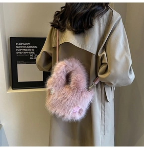 Pink faux fur bucket bag with a plush texture and star charm worn with a coat