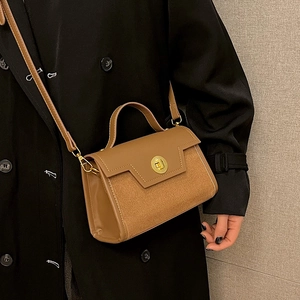 Brown leather crossbody bag with matte patchwork and golden knob clasp shown on a model