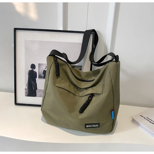 Close-up of olive green nylon crossbody bag featuring woven zipper pull and logo detail