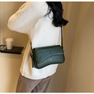 Detail of dark green vintage underarm bag with wavy flap and adjustable gold buckle strap