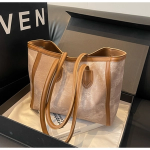 Macro shot of large tote bag with premium canvas texture and brown leather trim in a gift box