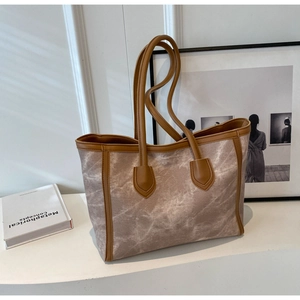 Detail of large tote bag with beige marble texture fabric and brown leather handles
