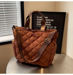 Detail of dark brown quilted puffer tote bag with wide strap and side pocket
