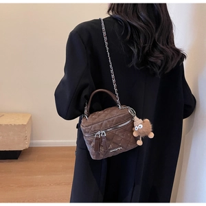 Rear view of brown quilted crossbody bucket bag with chain strap and plush charm