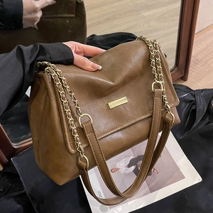 Brown leather tote bag with gold metal plaque and chain strap in vintage style