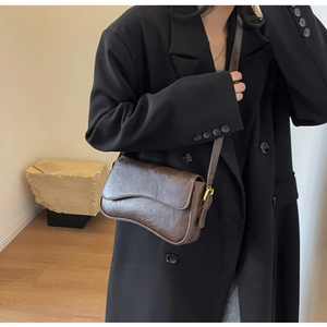 Detail of dark brown vintage crossbody bag with pleated texture and gold hardware on model