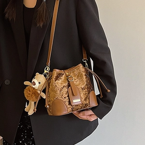 Sac seau en velours marron avec matelassage, finitions cuir et breloque ours sur bandoulière