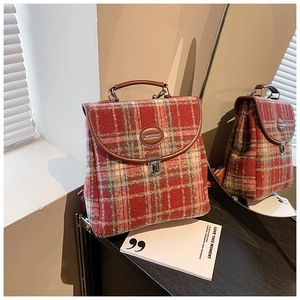 Close-up of red and blue plaid tweed backpack with leather handle and metal lock detail