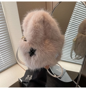 Close-up of fuzzy pink bucket bag with black star detail and white shoulder strap