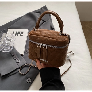 Detailed close-up of brown quilted bucket bag with chain strap and silver logo