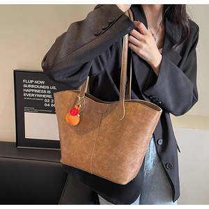 Detail view of brown tote bag with retro cloud texture and knit persimmon charm