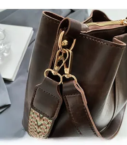 Detailed macro view of golden lobster clasp and colorful woven strap on a brown handbag