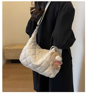 Detail of white quilted nylon hobo bag with a cute plush bear charm on the strap