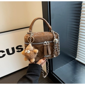 Detail of dark brown quilted crossbody bag with silver chain and plush charm