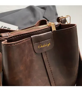 Close-up of vintage brown leather bucket bag with gold logo and premium metal zipper