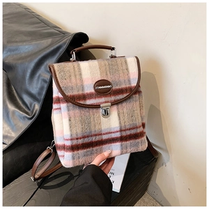 Close-up of pink plaid tweed backpack showing brown leather handle and metal buckle detail