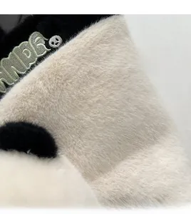 Détail du sac en peluche montrant la fourrure douce noir et blanc avec broderie verte
