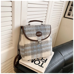Detail of tweed checkered backpack with leather trim and silver metal buckle closure