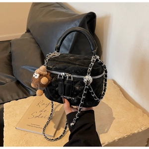 Quilted black bucket bag with silver chain and cute plush bear charm on stone base