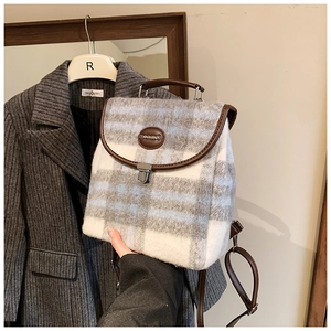 Detail of wool blend plaid backpack featuring leather handle and vintage metal buckle