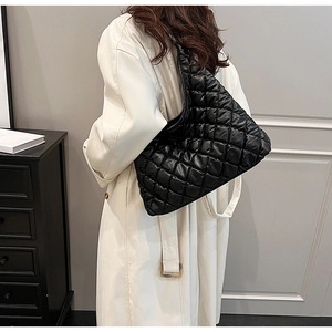 Quilted black puffer tote bag shown on model with chic cream trench coat for autumn style