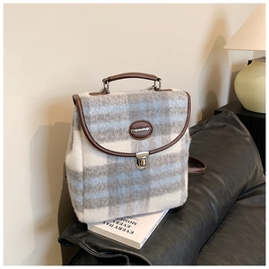 Detail of plaid wool backpack with brown leather trim and metal clasp lock closure