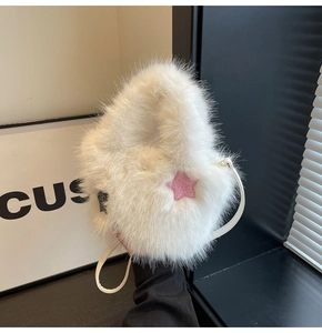 Detail view of white faux fur handbag featuring a pink rhinestone star patch