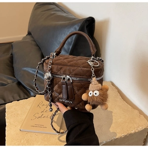 Macro view of dark brown quilted box bag with vintage texture and teddy bear charm