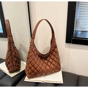 Detail of caramel brown quilted hobo tote bag with padded texture and sleek shoulder strap
