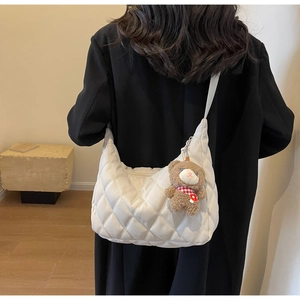 Detail of off-white quilted nylon tote bag with cute teddy bear charm on model back