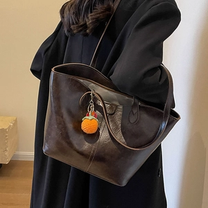 Minimalist vintage dark brown leather tote bag with glossy finish and orange charm accessory