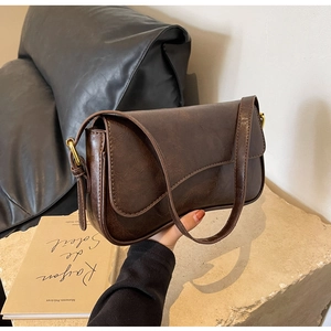 Detail of vintage dark brown faux leather underarm bag with antique gold metal ring buckle