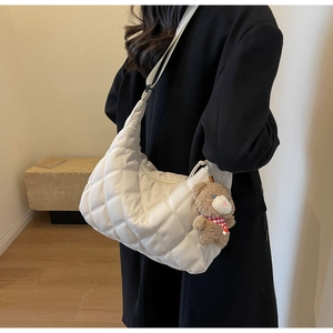 Close-up of cream quilted nylon tote bag featuring a cute plush bear charm detail
