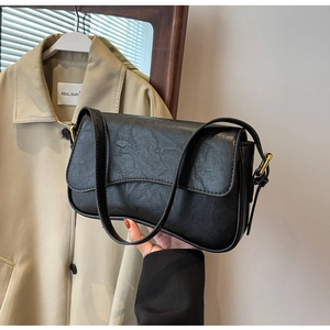 Detail shot of the black textured faux leather bag with vintage creases and flap closure