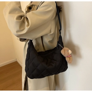 Close-up of black quilted nylon hobo bag with adjustable strap and cute bear charm