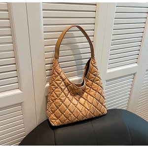Detail of light brown quilted hobo bag with rhombus pattern on stylish black chair