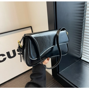 Detail of black glossy shoulder bag showing smooth faux leather texture and golden buckle