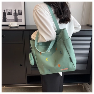 Detail of green canvas tote with colorful embroidery and matching mini coin purse charm