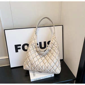 Detailed view of beige quilted tote bag with diamond stitching and puffy texture surface