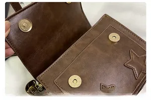 Close-up of brown vintage leather shoulder bag with star stitching and magnetic closure