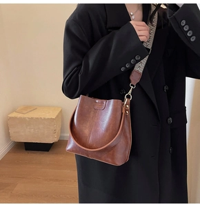Sac seau vintage marron avec large bandoulière jacquard porté à l'épaule du mannequin