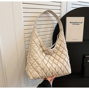 Detailed view of quilted cream tote bag showing diamond stitching and wide strap