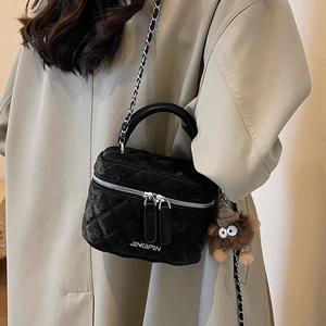 Quilted black mini chain bucket bag with JINGPIN logo worn by a model in a trench coat