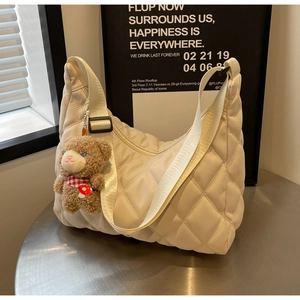 Detail of cream quilted nylon tote with adjustable strap and cute teddy bear charm