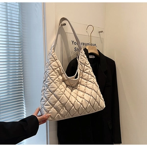 Detailed view of the large quilted diamond pattern on a creamy white puffer tote bag